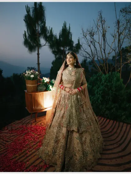 A beautiful evening portrait of the bride, her lehenga spread out on the steps, surrounded by flower petals and soft lights.
