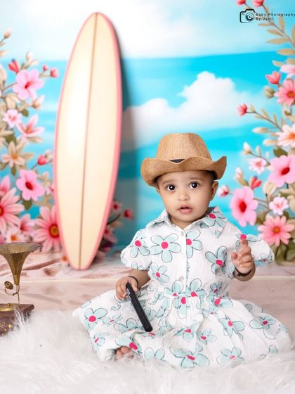 Getting into the beach spirit with a cute straw hat. This shot from the surf-themed session shows more of the setup, including a miniature gramophone and a floral garland.