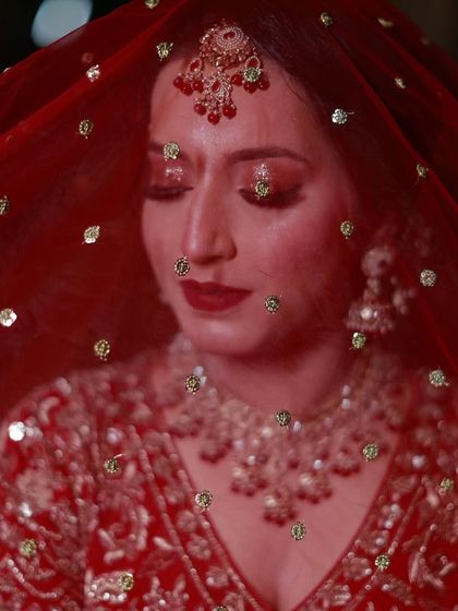 A beautiful portrait of Uzma under her red veil, showcasing her sparkling red eye makeup.