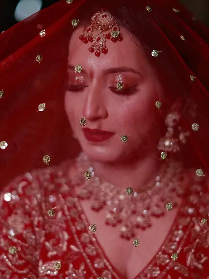 A beautiful portrait of Uzma under her red veil, showcasing her sparkling red eye makeup.