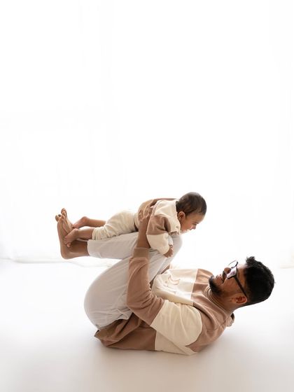 A father playfully lifting his baby in the air. This "airplane" pose is always a hit with the little ones and makes for a dynamic and joyful photo.