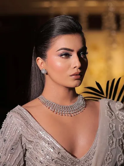 A chic and modern reception look. This fully embellished blouse with fringe details is paired with a sleek, high ponytail and a diamond necklace for a look that is sharp, stylish, and ready to party.