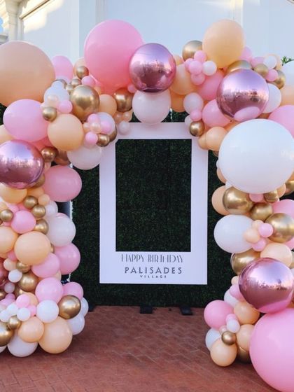 A picture-perfect frame for birthday memories. This balloon arch in shades of pink, peach, and gold creates a beautiful photo frame, perfect for an outdoor party.