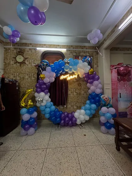 A fun 4th birthday party setup with a 'Frozen' theme, using blue, purple, and white balloons and a character cutout.
