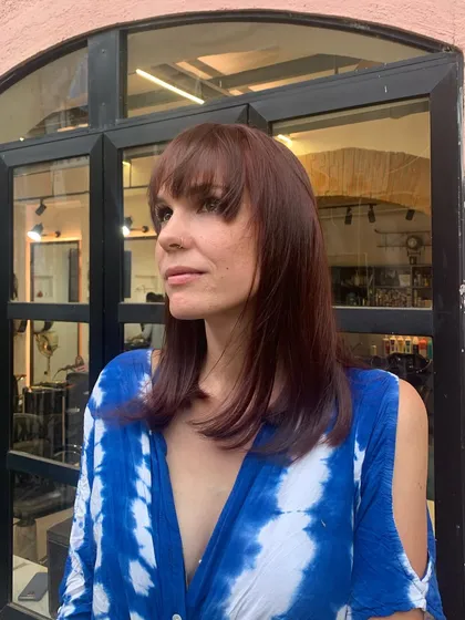 A gorgeous "Cinnamon Roll" color on a modern lob with a full fringe. The reddish-brown hue is warm and spicy, and the bangs give the style a bold, fashionable edge.