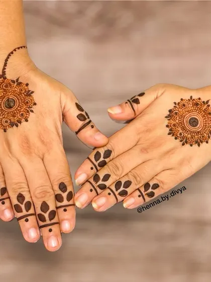 A classic minimalist choice, this design features a delicate mandala on the back of the hand connected to the wrist with a simple dotted line. The fingers have a simple leafy pattern, keeping the look light and airy.