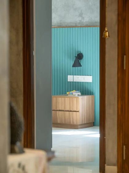 A glimpse into a bedroom, where a fluted turquoise wall provides a vibrant pop of color against the neutral and wood-toned palette.