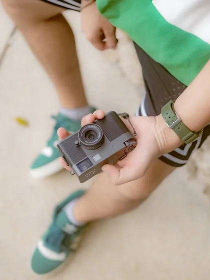 A detailed shot focusing on the Fujifilm X half camera held in hand. This type of image is great for showing the product's design, size, and ergonomics in a natural, lifestyle context.