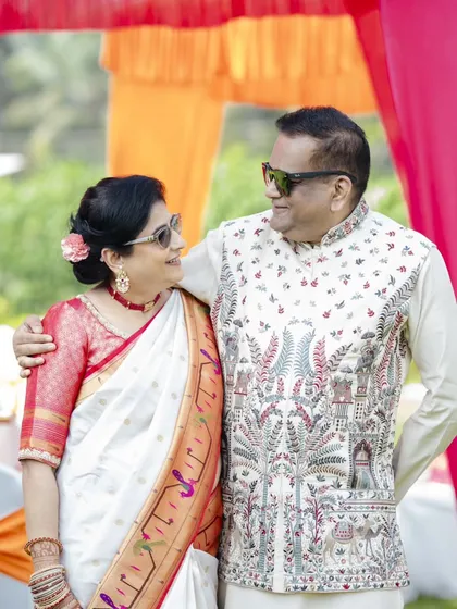 The mother of the bride looking chic and happy at the Haldi ceremony. Her look features a classic updo with a fresh flower, paired with simple makeup and cool sunglasses for the outdoor event.