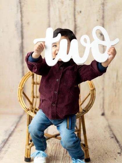 A playful peek-a-boo moment with the 'two' sign during a second birthday milestone session.