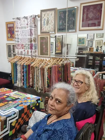 A candid moment in my studio with a visitor. The space is filled with finished pieces, from framed art to sarees, showcasing the breadth of my work.