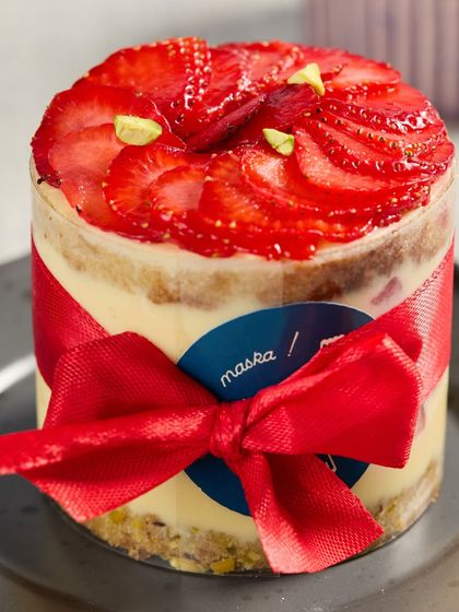 Our Pistachio & Strawberry Cream Cake, beautifully decorated with a red ribbon for gifting.