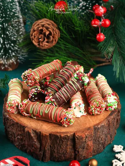 A different view of the festive chocolate rolls, with more of the green pine branches visible. This enhances the Christmas mood of the shot.