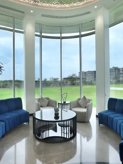 This spacious lounge area features floor-to-ceiling curved windows that flood the space with natural light. The deep blue sofas provide a bold color contrast, creating a modern and inviting space for residents to relax and socialize.