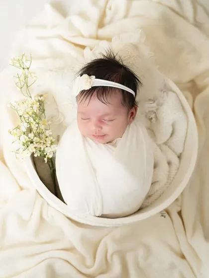A peaceful newborn portrait, styled with delicate baby's breath flowers and soft, cream-coloured fabrics for a pure and angelic look.