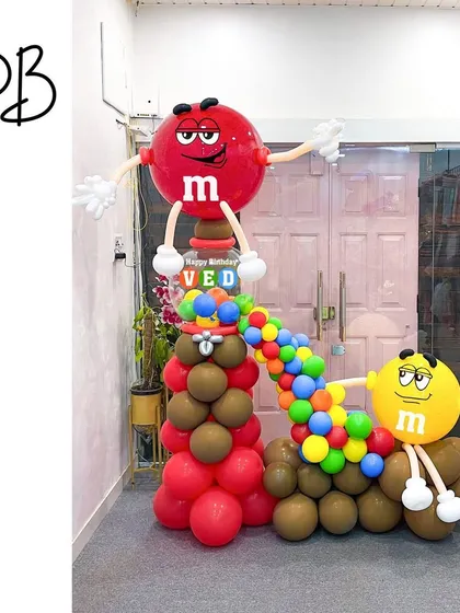 This M&M's balloon sculpture is a sweet treat for any candy lover's party. The iconic Red and Yellow characters are brought to life with a cascade of colorful candy-like balloons flowing between them.