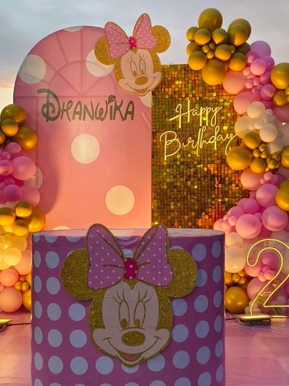 An outdoor Minnie Mouse theme for a second birthday, with a gold sequin and pink polka-dot backdrop, perfect for sunset parties.