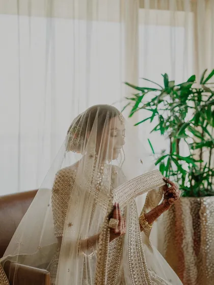 The bride getting ready in a sunlit room. This candid shot captures a moment of quiet preparation, the light from the window creating a soft and ethereal glow.
