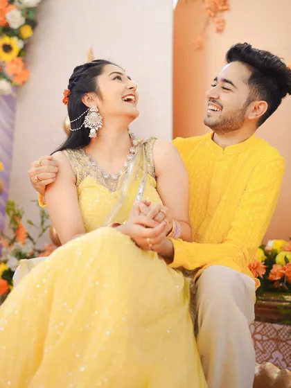 A candid moment of shared laughter between the couple during their Haldi. Dressed in coordinated yellow outfits, their connection shines through, making for a perfect, happy portrait.
