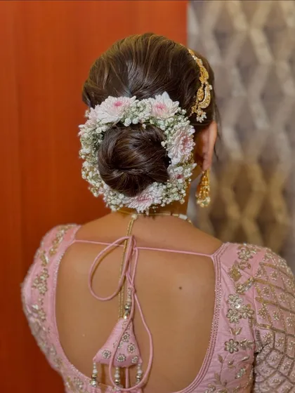 A full circle of delicate pink and white flowers around a classic bun. This hairstyle is perfect for a bride who loves a soft, floral look.