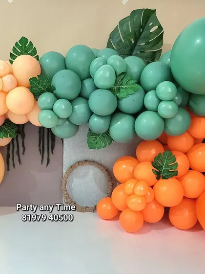 This organic balloon garland in pastel orange, green, and teal with monstera leaves is great for a jungle theme baby photoshoot or cake smash.