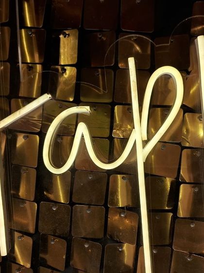 A close-up of the 'Happy Anniversary' neon sign against the sparkling gold sequin wall. This combination adds a modern yet timeless touch to any anniversary celebration.
