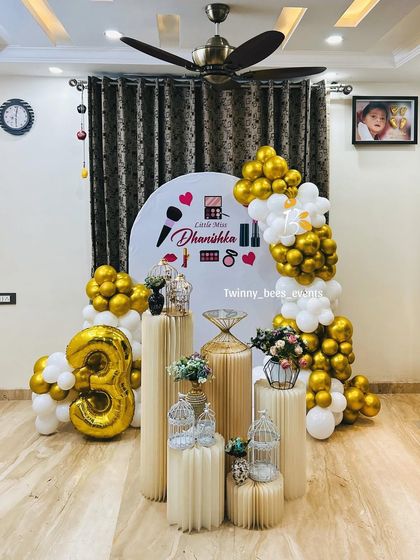 A fun and chic makeup-themed party for little Miss Dhanishka's 3rd birthday. The decor included a custom backdrop with cosmetic graphics, a gold and white balloon arrangement, and a large foil number '3' balloon.