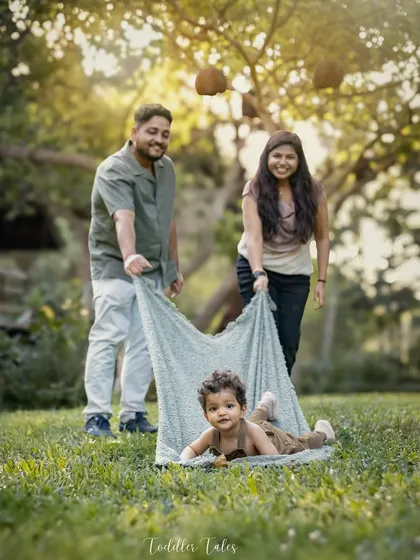 A fun and playful family moment outdoors, with parents pulling their child along on a blanket. I love capturing these candid, action-filled shots that show a family's unique dynamic.