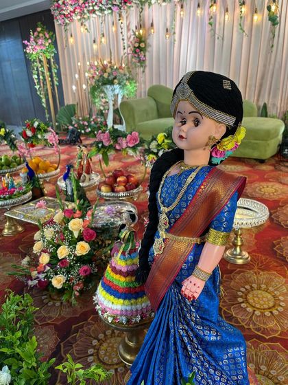 A doll dressed in a traditional blue saree, part of a larger decorative arrangement.