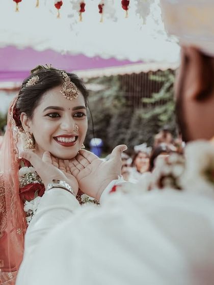A beautiful, candid moment where the groom gently holds the bride's face. Her smile shows the deep connection and happiness of the ceremony.