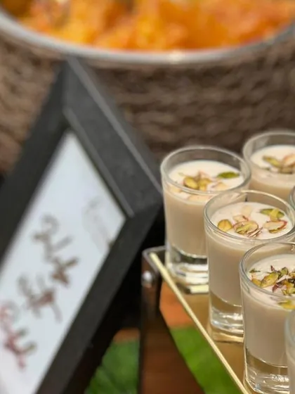 Close-up of our Thandai shots, a perfect welcome drink for an outdoor party. These traditional coolers are garnished with pistachios and served chilled.