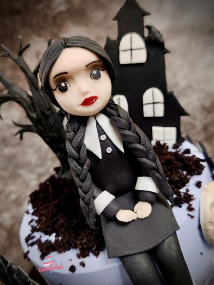 A close-up of the handcrafted Wednesday Addams figurine, capturing her iconic braids, dress, and stoic expression.
