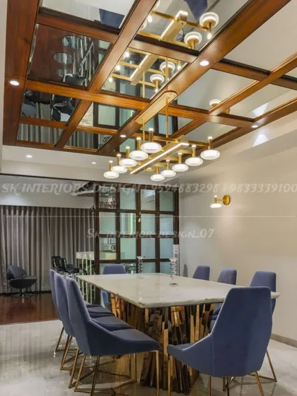 We designed this dining space with a dramatic coffered ceiling featuring wood and mirror panels. The large marble-topped table is surrounded by plush blue velvet chairs, creating a formal and opulent setting for meals.