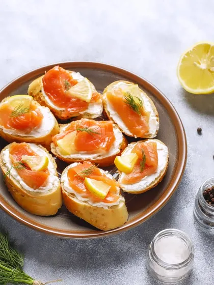 Smoked Salmon and Cream Cheese Crostini. A classic combination of silky salmon and creamy cheese on a crisp slice of bread, finished with a squeeze of lemon and fresh dill.