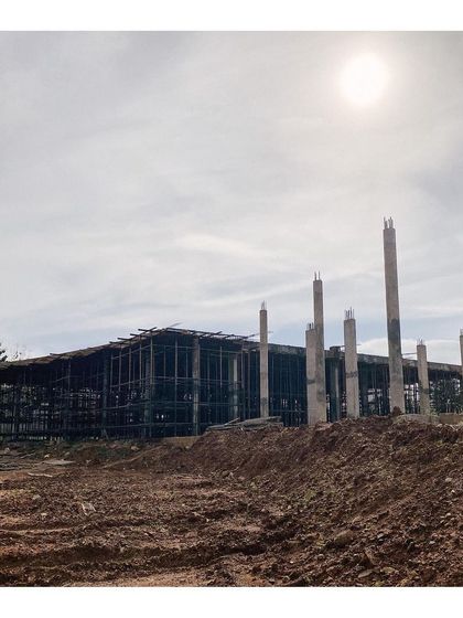 The steel framework of the main building under construction, with concrete pillars rising from the earth. This image documents the early stages of the project, showing the bones of the structure before the walls were added.