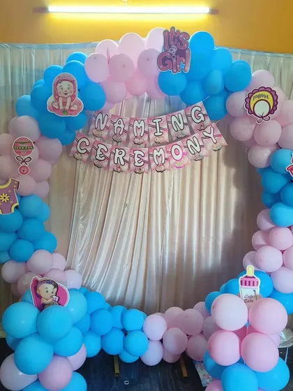 A cheerful and simple naming ceremony decoration with a pink and blue balloon ring and a "Naming Ceremony" banner.