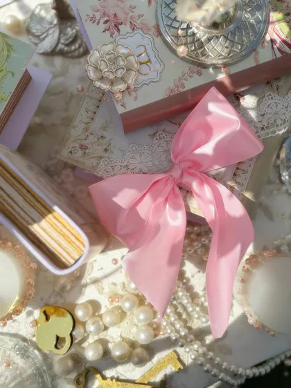 More details from the Bridgerton luncheon, featuring a pink satin bow, vintage books, and custom embellishments that add to the romantic and personalized feel of the event.