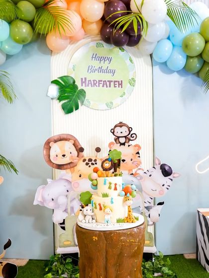 The beautiful safari-themed cake perfectly integrated into the main backdrop, surrounded by friendly jungle animals.