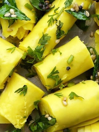 A close-up view of our freshly made Khandvi rolls, garnished with cilantro and tempered spices. The soft, pillowy texture is a hallmark of this beloved Gujarati snack.
