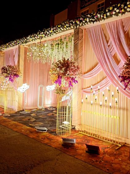 Here is another style of a classic wedding entrance. This setup features draped pink fabric, large floral arrangements on caged stands, and rows of electric candles to light the way.