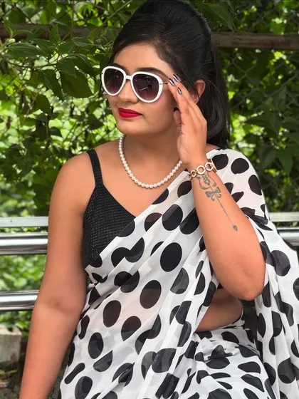 A full retro glam look. This vintage style features a polka dot saree, classic winged eyeliner, a bold red lip, and oversized white sunglasses.