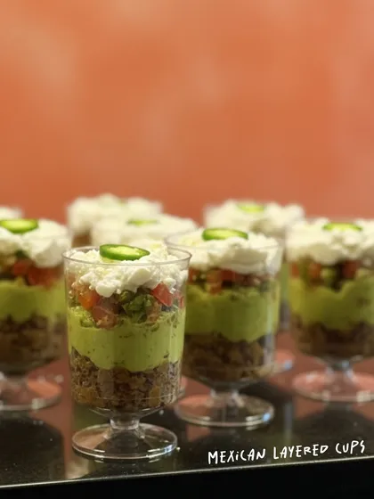 These Mexican Layered Cups are always the life of the party. Each cup is a perfect, individual portion of layered beans, fresh guacamole, zesty salsa, and cool sour cream, finished with a jalapeño kick.