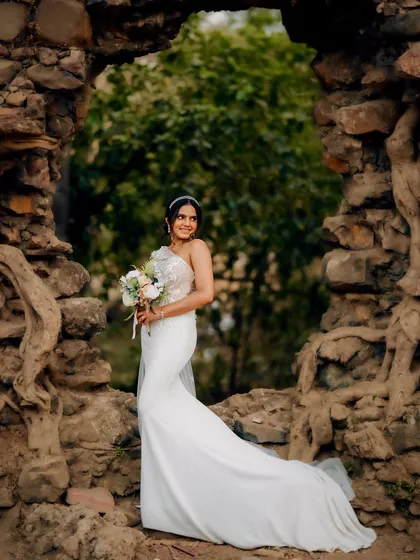A joyful bridal portrait in a rustic stone archway. The bride's smile and the beautiful setting come together for a perfect wedding day photo.
