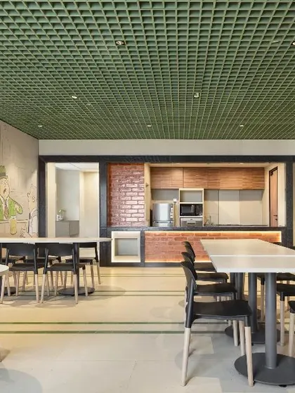 The cafeteria at the Bestseller office, featuring a playful wall mural and a green grid ceiling. The design creates a casual, vibrant, and energizing atmosphere for employees to relax and recharge.