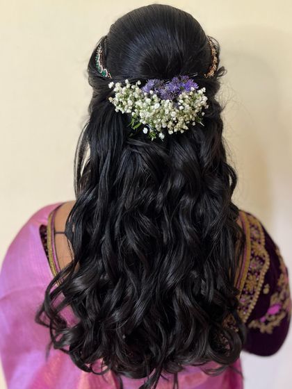 The hairstyle for Niveditha's reception. A beautiful half-up, half-down style with soft waves, adorned with delicate fresh flowers.
