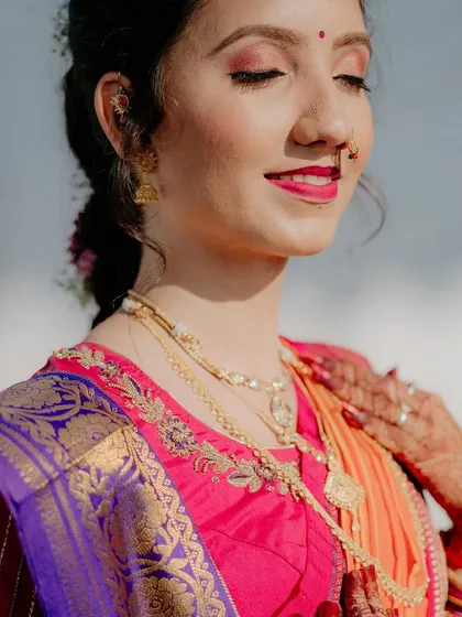 A sun-kissed portrait of the bride with her eyes closed, basking in the warm light. Her vibrant makeup and paithani saree look stunning.
