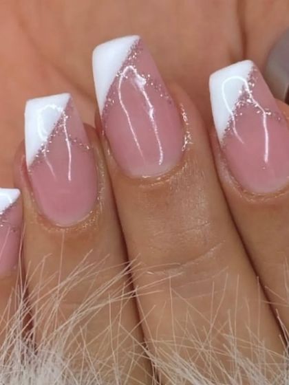 A modern French manicure with an angular white tip and a subtle silver glitter line separating it from the nude base.