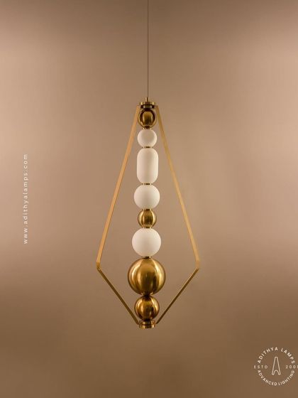 This elegant pendant is framed by a triangular gold structure, enclosing a string of white and gold beads. It's a sophisticated and modern piece that adds a touch of jewelry-like decoration to your space.