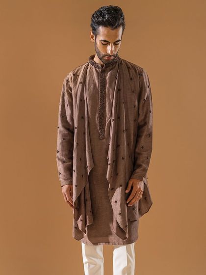 A unique, draped kurta in a muted brown tone. The asymmetrical overlay and delicate embroidery create a contemporary silhouette that is both trendy and traditional.