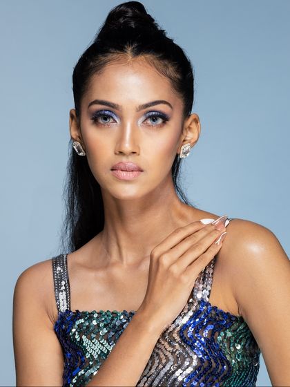 A classic beauty headshot with a direct gaze. The shot highlights the model's features, the precise makeup, and the elegant diamond stud earrings.
